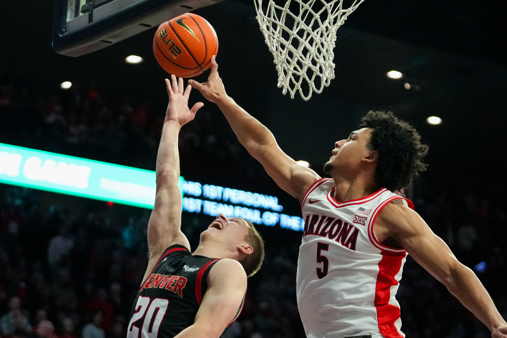 Arizona Wildcats guard Brayden Burries, right, blocks the shot a Denver Pioneers guard Carson Johnson, left, during the first half of an NCAA college basketball game Monday, Nov. 24, 2025, in Tucson, Ariz. (AP Photo/Darryl Webb)