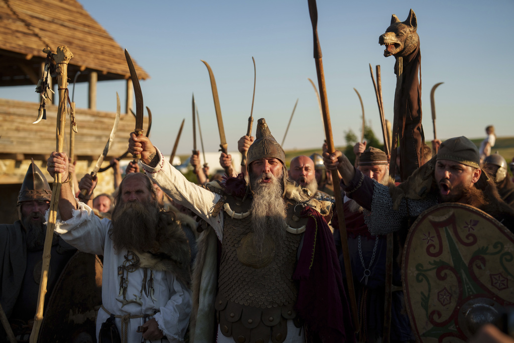 Members of historical reenactment groups wearing Dacian warrior outfits, wave their weapons in Poiana, Romania, Sunday, July 13, 2025, during the Getodava historical reenactment festival. (AP Photo/Vadim Ghirda)