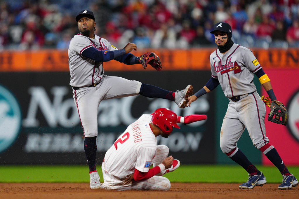 Atlanta Braves' Ozzie Albies, top left, attempts a double play after a force out of Philadelphia Phillies' Justin Crawford, bottom left, during the fifth inning of a baseball game, Sunday, April 19, 2026, in Philadelphia. (AP Photo/Derik Hamilton)
