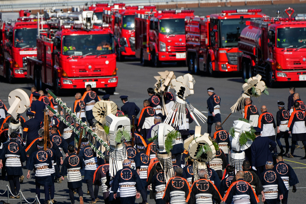 Members of a traditional firefighting preservation group retreat from the venue near latest fire engines during the annual New Year's Fire Brigade Review Tuesday, Jan. 6, 2026, in Tokyo. (AP Photo/Eugene Hoshiko)