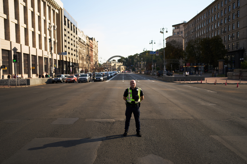 A police officer observes a daily nationwide minute of silence in memory of soldiers killed in the war with Russia, in Kyiv, Monday, Aug. 17, 2026. (AP Photo/Francisco Seco)