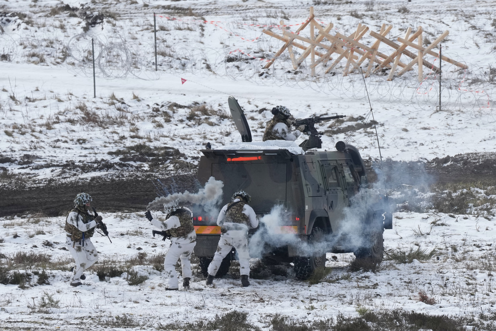 Soldiers throw smoke bombs as they work to extract and secure an enemy in a mock village during NATO led military exercises at a military base near Bergen, Germany, Thursday, Feb. 19, 2026. (AP Photo/Virginia Mayo)