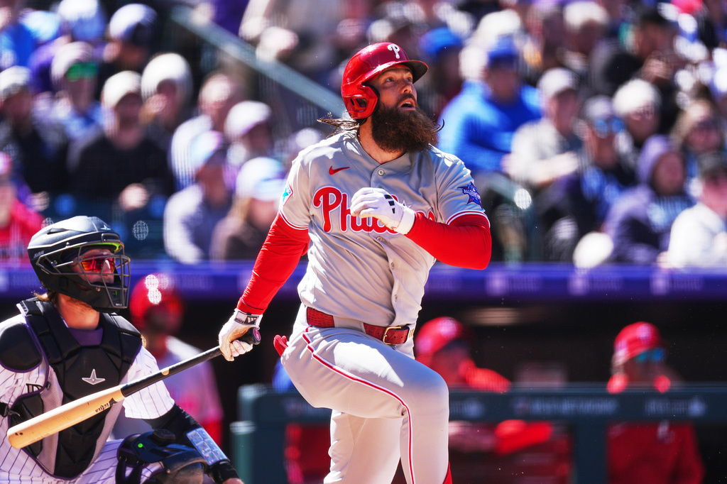 Philadelphia Phillies' Brandon Marsh, right, follows the flight of his three-run home run off Colorado Rockies starting pitcher Michael Lorenzen in the first inning of a baseball game Friday, April 3, 2026, in Denver. (AP Photo/David Zalubowski)
