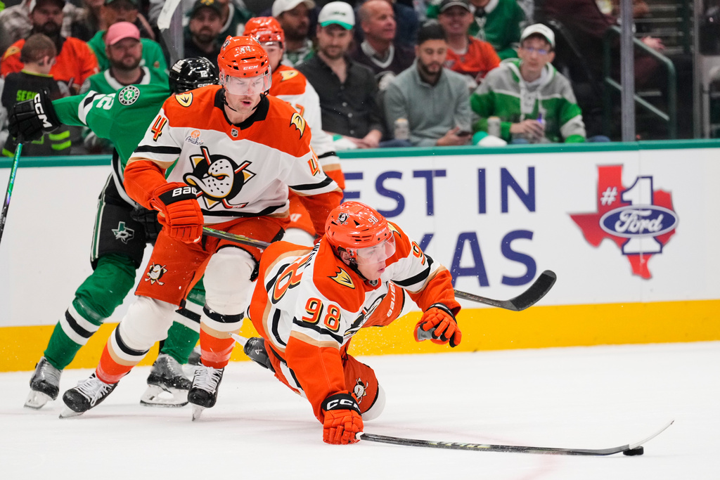 Anaheim Ducks' Pavel Mintyukov (98) is tripped by Dallas Stars' Radek Faksa, left rear, as Ross Johnston (44) looks on in the first period of an NHL hockey game Thursday, Nov. 6, 2025, in Dallas. (AP Photo/Tony Gutierrez)