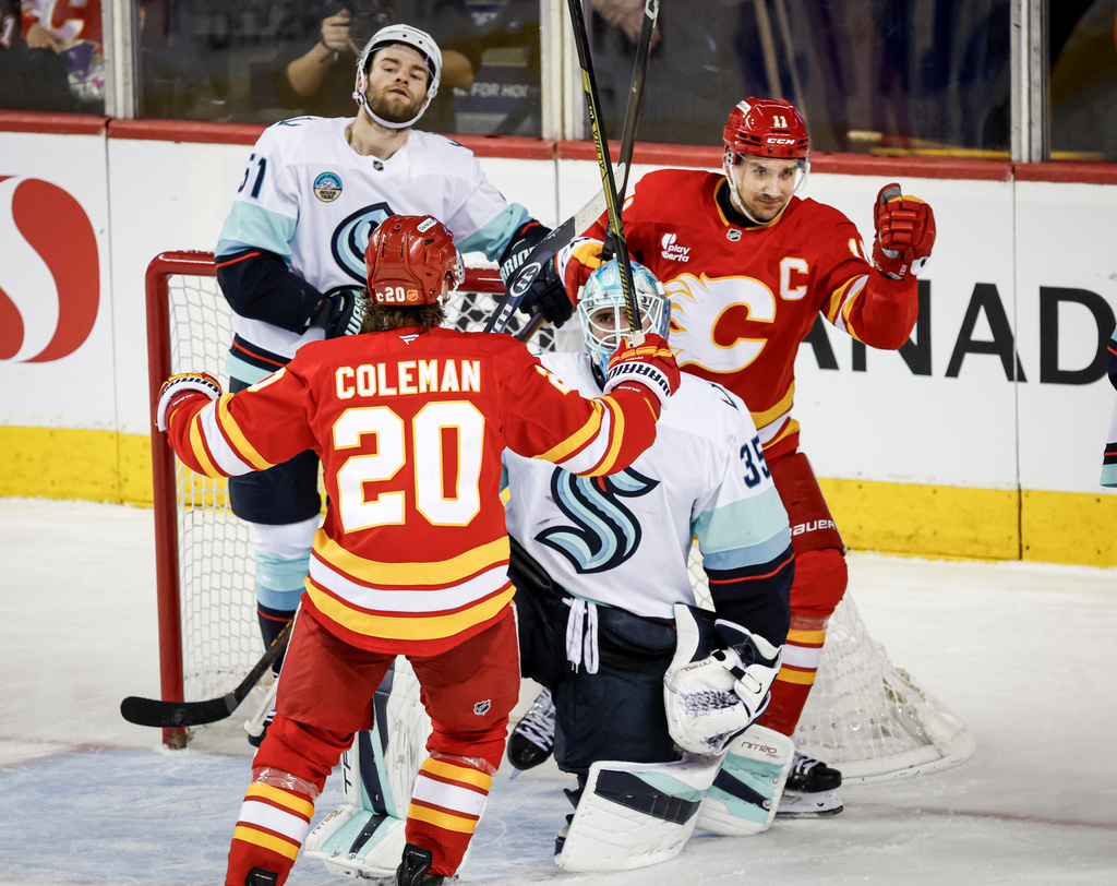 Seattle Kraken's Shane Wright, left, and goalie Joey Daccord react as Calgary Flames' Mikael Backlund, right, celebrates his goal with teammate Blake Coleman, centre, during the second period of an NHL hockey game, in Calgary, Alberta, Thursday, Dec. 18, 2025. (Jeff McIntosh/The Canadian Press via AP)
