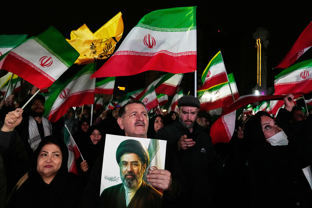 Pro-government supporters wave national flags as one of them holds a picture of the Supreme Leader Ayatollah Mojtaba Khamenei during a rally in a square in western Tehran, Iran, Wednesday, March 25, 2026. (AP Photo/Vahid Salemi)