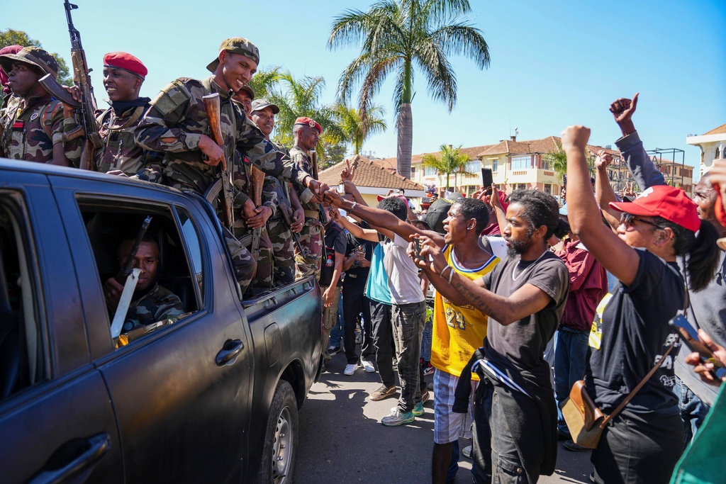 Soldiers are greeted by people gathering for a ceremony in tribute to demonstrators killed during recent anti-government protest in Antananarivo, Madagascar, Sunday, Oct. 12, 2025. (AP Photo/Mamyrael)