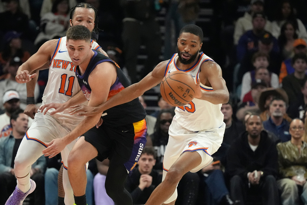 New York Knicks guard Mikal Bridges, right, steals the ball from Phoenix Suns guard Collin Gillespie, left, during the first half of an NBA basketball game, Friday, Jan. 9, 2026, in Phoenix. (AP Photo/Ross D. Franklin)