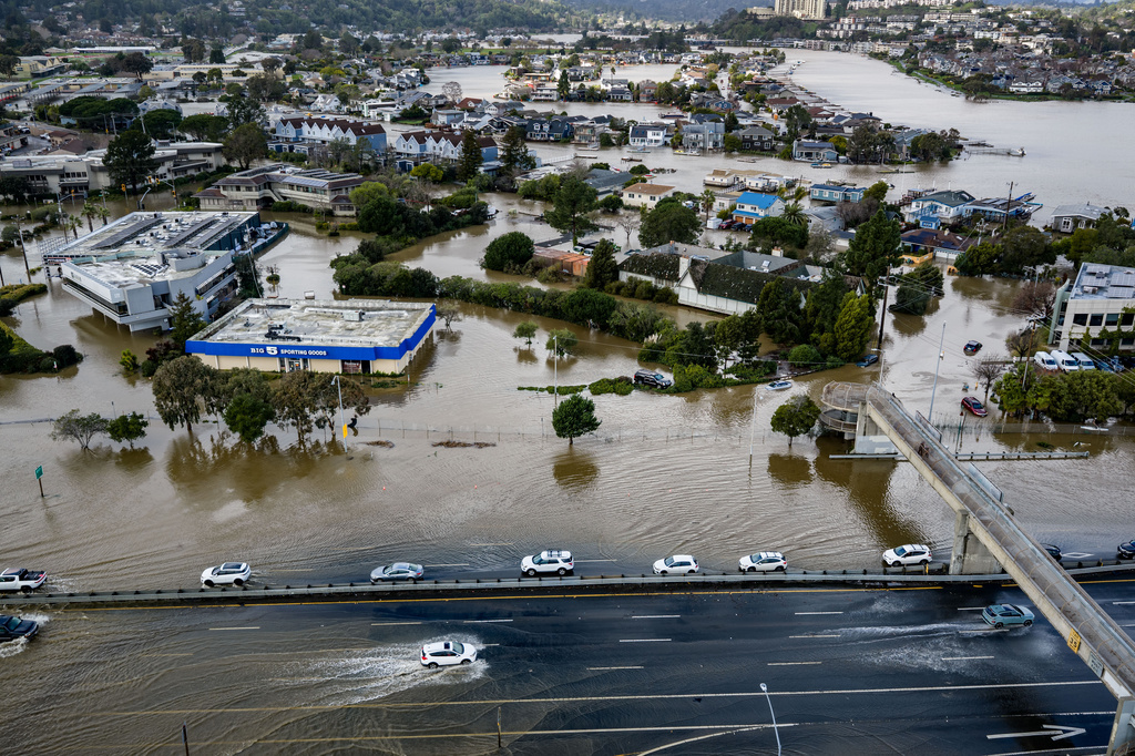 FILE - Cars drive on highway 101 flooded by a king tide, the year's highest tides, Jan. 3, 2026, near Corte Madera in Marin County, Calif. (AP Photo/Ethan Swope, File)