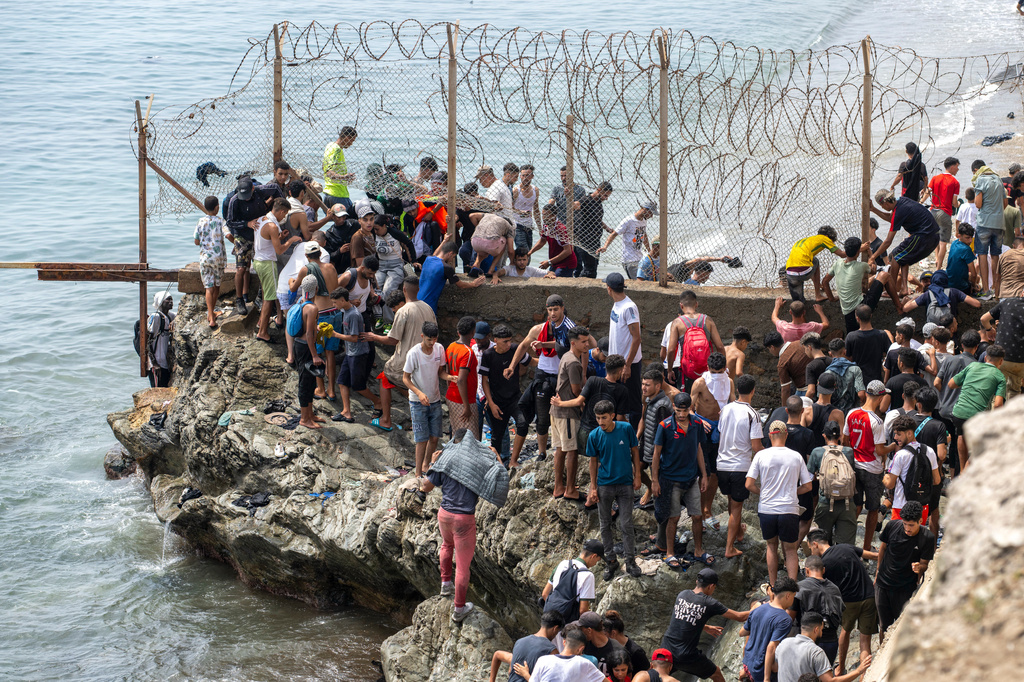People breach barbed wires as they attempt to cross from the Moroccan northern town of Fnideq to the Spanish enclave of Ceuta, Friday, July 31, 2026. (AP Photo)