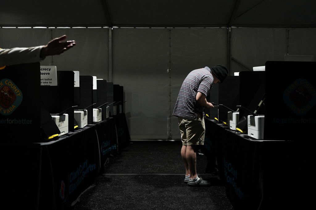 A voter looks at his phone while casting a ballot at a vote center set up in a tent in Las Vegas, Tuesday, June 9, 2026. (AP Photo/Jae C. Hong)