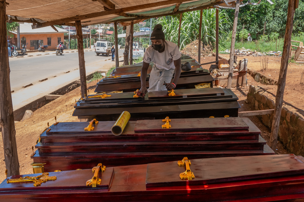Djakisa Christian, 18, a funeral home manager, dusts coffins for sale at his shop in Bunia, Congo, Friday, May 22, 2026. (AP Photo/Moses Sawasawa)