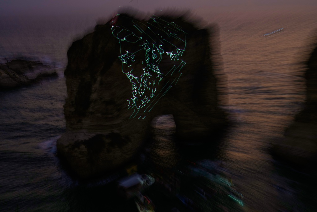 The landmark Raouche sea rock is illuminated by a portrait of late Hezbollah leader Hassan Nasrallah during an event commemorating his death in Israeli airstrikes nearly a year ago, in Beirut, Lebanon, Thursday, Sept. 25, 2025. (AP Photo/Hussein Malla)