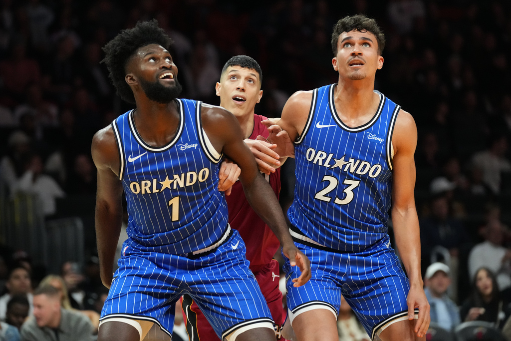 Miami Heat forward Simone Fontecchio (0) is pushed back by Orlando Magic forwards Jonathan Isaac (1) and Tristan da Silva (23) during the second half of an NBA basketball game Wednesday, Jan. 28, 2026, in Miami. (AP Photo/Marta Lavandier)