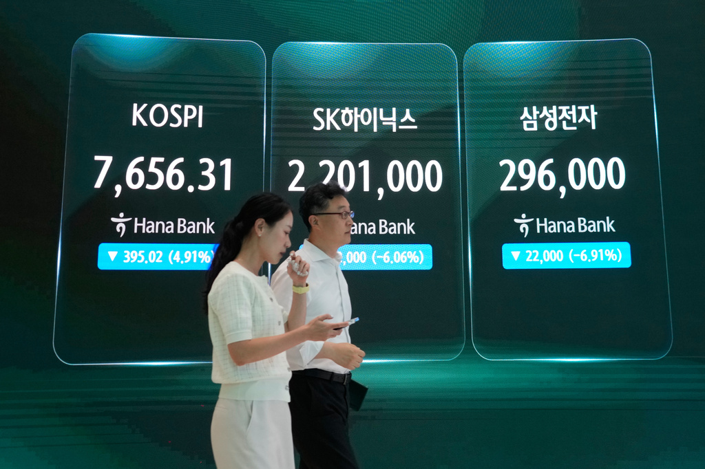 Currency traders pass by a screen showing the Korea Composite Stock Price Index (KOSPI), left, SK Hynix and Samsung Electronics Co., right, stock price at the foreign exchange dealing room of the Hana Bank headquarters in Seoul, South Korea, Tuesday, July 7, 2026. (AP Photo/Ahn Young-joon)