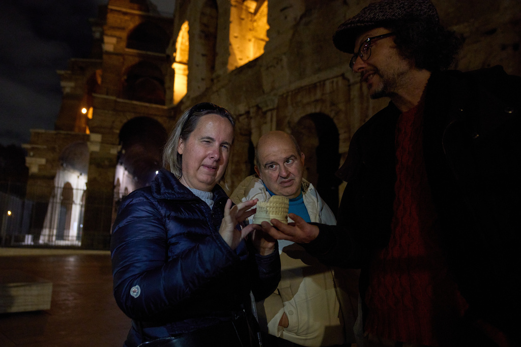 Michela Marcato, left, who is blind, and her partially sighted partner Massimiliano Naccarato examine a scale model of the Colosseum with Giorgio Guardi, right, a guide in inclusive tourism, in Rome, Dec. 17, 2025. (AP Photo/Alessandra Tarantino)