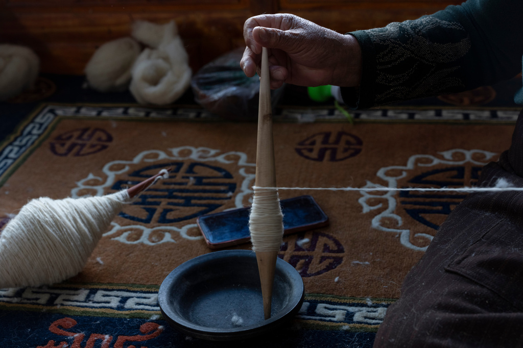 A worker pulls wool into a yarn at the Ethnic Huaji Handwoven Cooperative in Shannan in western China's Tibet Autonomous Region on July 23, 2026, as seen during a government organized visit for foreign journalists. (AP Photo/Ng Han Guan)