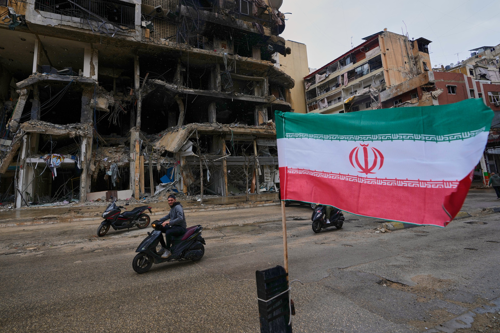 A man on his scooter passes next to an Iranian flag placed in front of a destroyed building, following a ceasefire between Hezbollah and Israel, in Dahiyeh, Beirut's southern suburbs, Lebanon, Monday, April 20, 2026. (AP Photo/Hussein Malla)