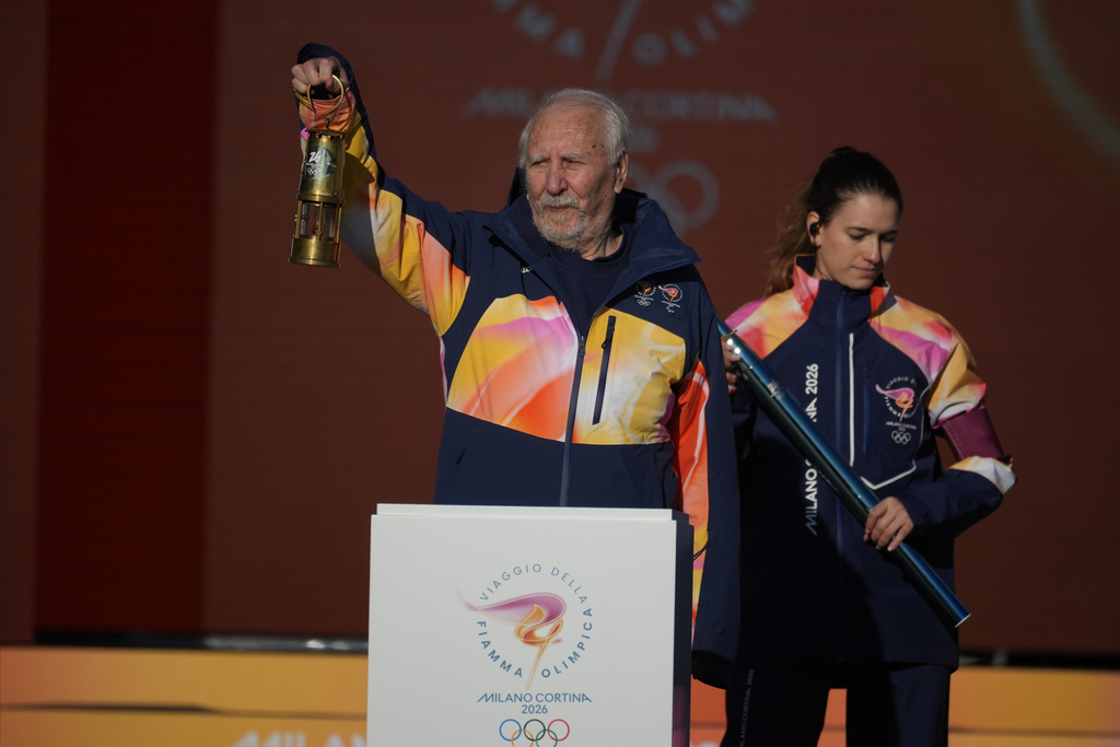 Former Italian track athlete Giancarlo Peris, 84, left, who was the final bearer of the Olympic torch for the 1960 Summer Olympics in Rome, holds a lantern with the Olympic flame ahead of the start of the 2026 Milan Cortina Winter Olympics torch ceremony in Rome as it begins its journey through Italy, Saturday, Dec. 6, 2025. The journey will conclude in Milan in February 2026. (AP Photo/Andrew Medichini)