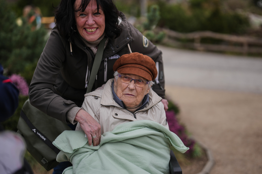 Ingrid Barkow, left, is wrapped in a blanket by her daughter Manuela Grudda, during a guided tour for people with dementia organized by Malteser Deutschland, part of the international Catholic aid organization Malteser Order of Malta, at the Zoo in Berlin, Germany, Thursday, March 26, 2026. (AP Photo/Markus Schreiber)