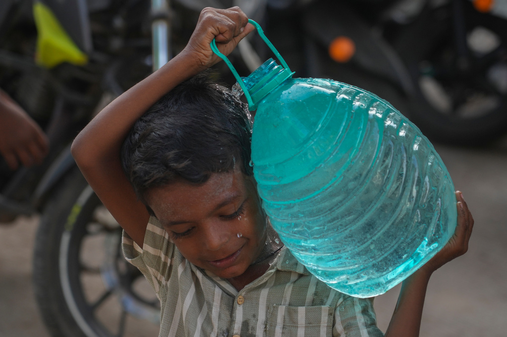 A boy carries a water can which he collect from a public tap in Mumbai, India, Saturday, June 20, 2026. (AP Photo/Rafiq Maqbool)