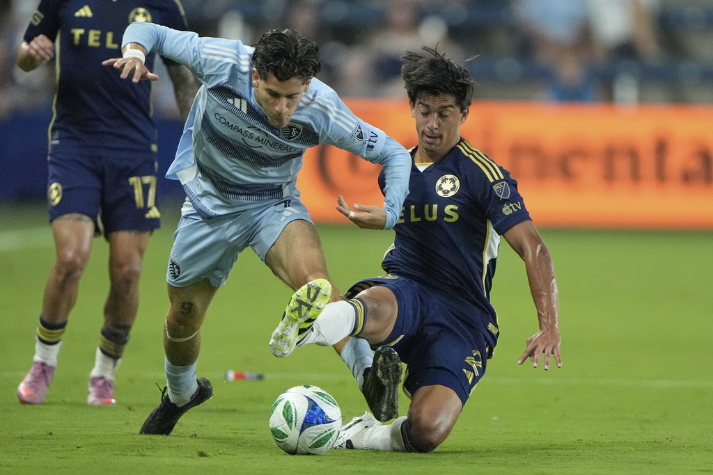Sporting Kansas City midfielder Santiago Munoz, left, and Vancouver Whitecaps defender Mathias Laborda (2) battle for the ball during the first half of an MLS soccer match Saturday, Sept. 20, 2025, in Kansas City, Kan. (AP Photo/Charlie Riedel)