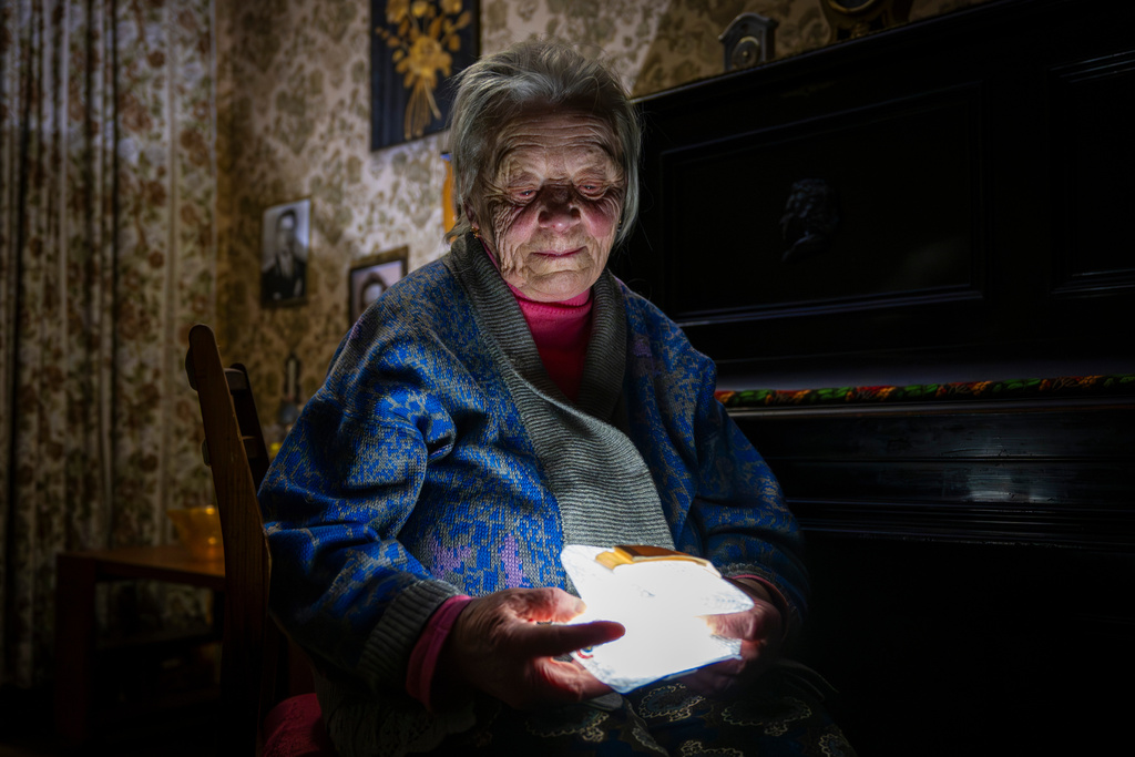 Raisa Derhachova holds a homemade flashlight during a power outage caused by regular Russian air strikes on the country's energy facilities in Kyiv, Ukraine, Tuesday, Jan. 13, 2026. (AP Photo/Dan Bashakov)