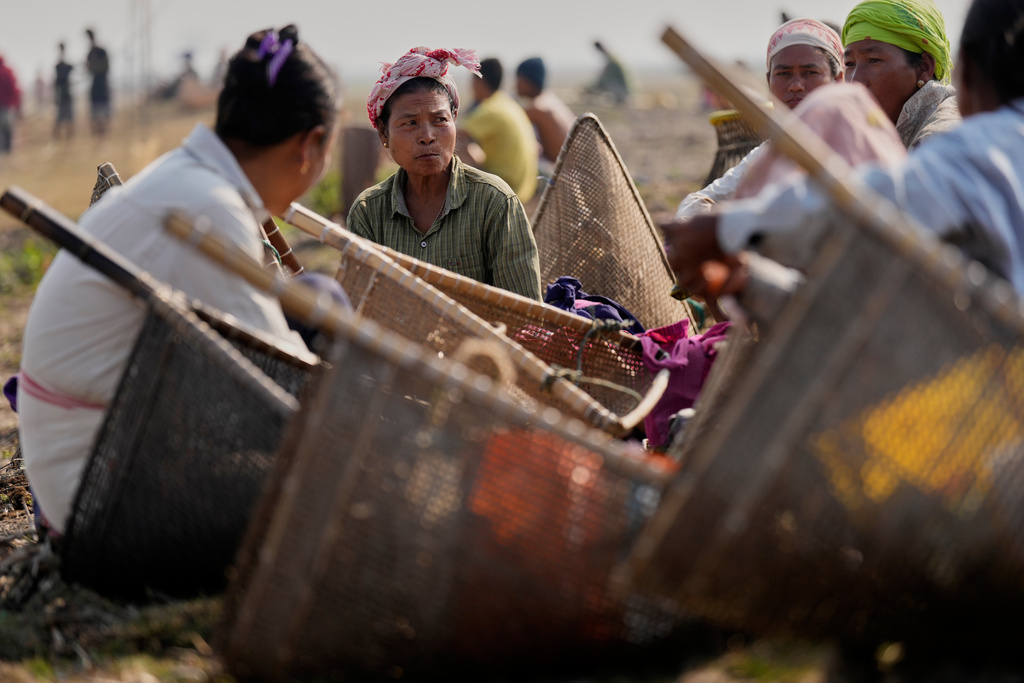 Tribal women with their fishing tools wait to participate in a community fishing as part of Bhogali Bihu celebrations which mark the end of the harvest season at Jalikhora village east of Guwahati, India, Tuesday, Jan. 13, 2026. (AP Photo/Anupam Nath)