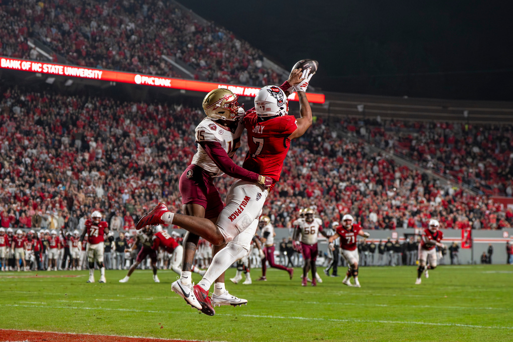 North Carolina State tight end Justin Joly (7) catches a pass over Florida State defensive back Shamar Arnoux (15) during the second half of an NCAA college football game, Friday, Nov. 21, 2025, in Raleigh, N.C. (AP Photo/David Yeazell)