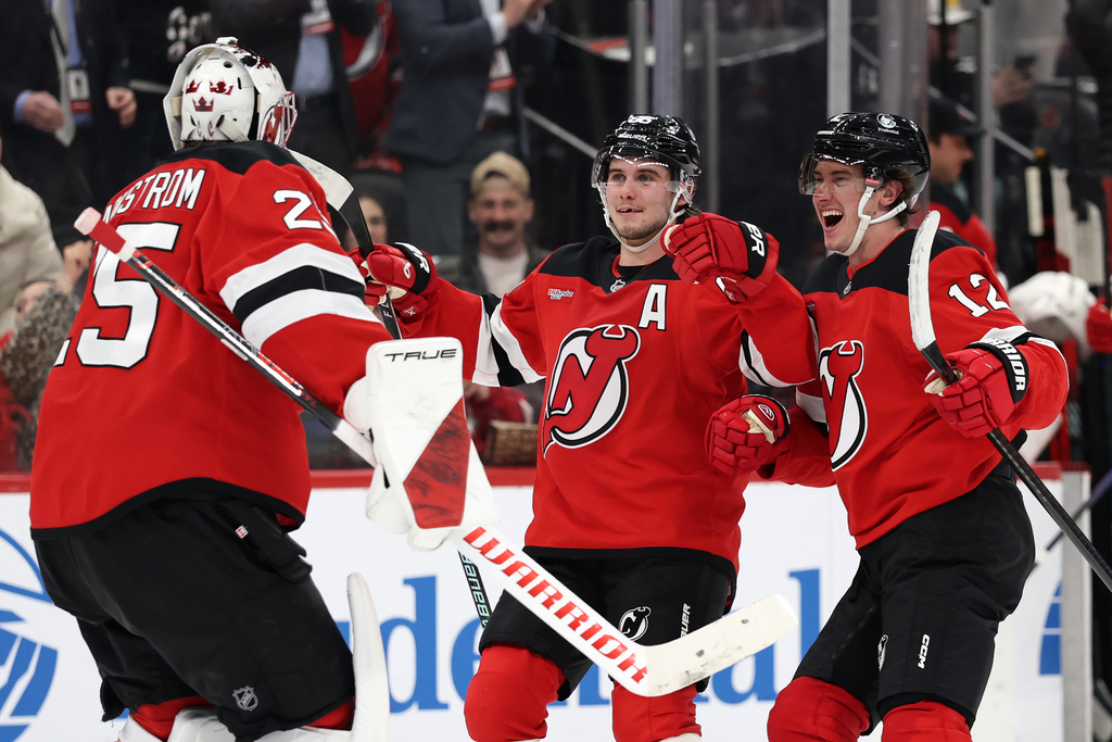 New Jersey Devils center Jack Hughes and Cody Glass (12) celebrate with goaltender Jacob Markstrom (25) after defeating the Toronto Maple Leafs in a shootout of an NHL hockey game Wednesday, March 4, 2026, in Newark, N.J. (AP Photo/Adam Hunger)
