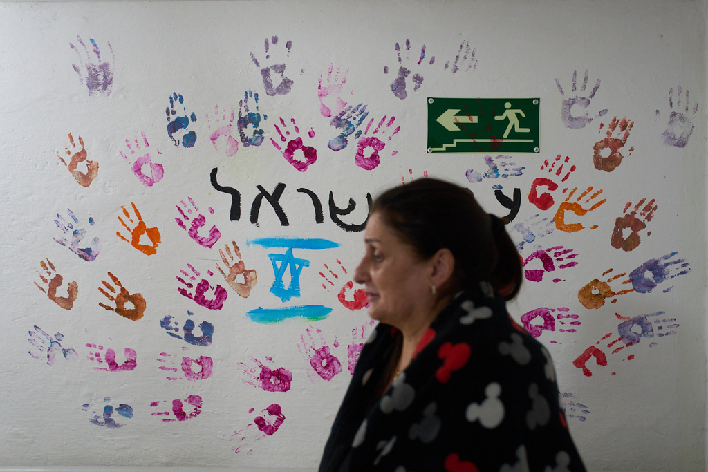 Bruria Danino takes shelter while air raid sirens warn of incoming Iranian and Hezbollah missile strikes in Kiryat Shmona, northern Israel, Monday, March 16, 2026. (AP Photo/Ariel Schalit)