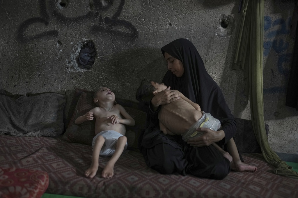 Samah Matar poses for a photo with her sons, Yousef, 6, in her arms, and Amir, 4, affected by malnutrition and cerebral palsy, at a U.N.-run school in Gaza City, July 26, 2025. (AP Photo/Jehad Alshrafi)