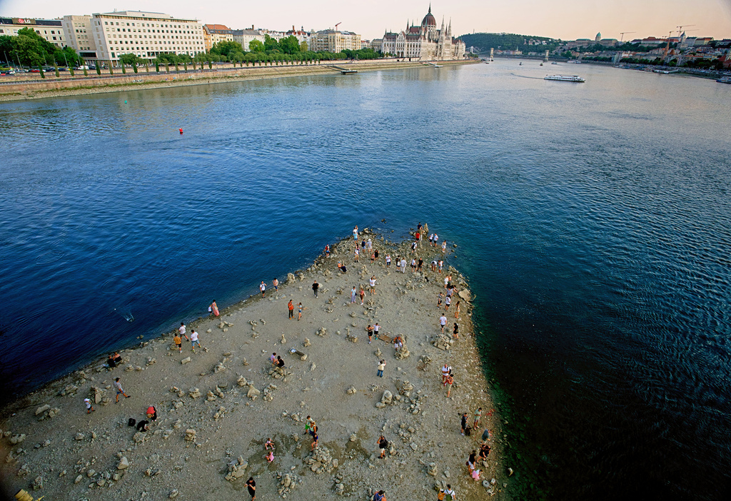 FILE - People walk on a sandbar underneath the Danube's Margareth Bridge in downtown Budapest, Hungary, on Aug. 5, 2026, as the river, which runs through 10 European countries, has receded never-before-seen low water levels. (AP Photo/Bela Szandelszky, File)