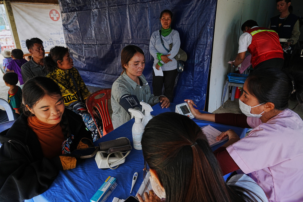 Evacuated people, left, receive medical check up as they take refuge at Batthkoa primary school in Oddar Meanchey province, Cambodia Wednesday, Dec. 10, 2025, after fleeing homes following fighting between Thailand and Cambodia over territorial claims. (AP Photo/Heng Sinith)