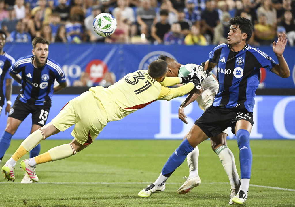 Austin FC's Myrto Uzuni, second from right, scores against CF Montreal goalkeeper Thomas Gillier (31) as Montreal's Efrain Morales (24) defends during first-half MLS soccer match action in Montreal, Saturday, Aug. 23, 2025. (Graham Hughes/The Canadian Press via AP)
