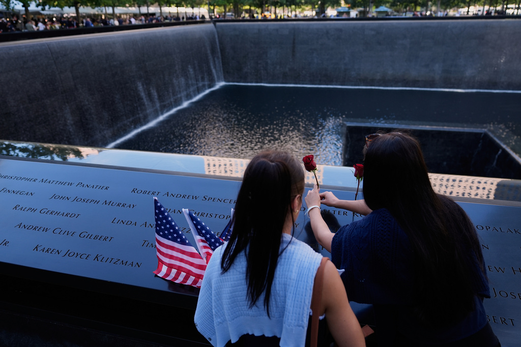 FILE - Ainsley, right, and Sarah Jurccak place a flower in the name of a relative during a ceremony to mark the 24th anniversary of the 9/11 attacks, Sept. 11, 2025, in New York. (AP Photo/Seth Wenig, File)
