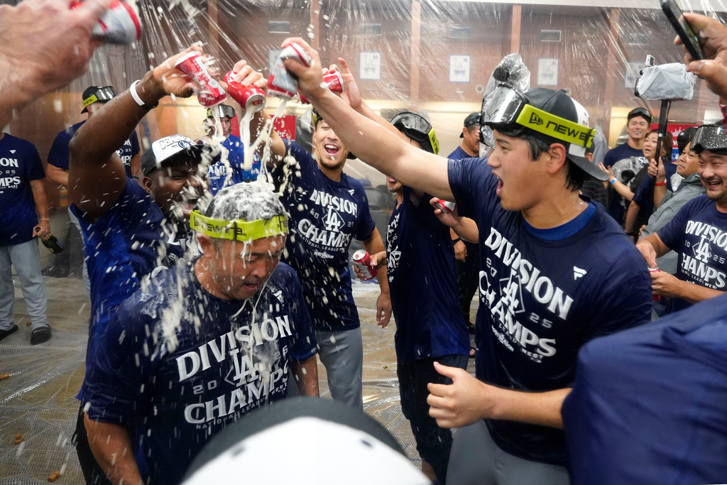 Los Angeles Dodgers two-way player Shohei Ohtani, right, celebrates with his teammates after the Dodgers clinched the National League West title against the Arizona Diamondbacks during a baseball game at Chase Field Thursday, Sept. 25, 2025, in Phoenix. (AP Photo/Darryl Webb)