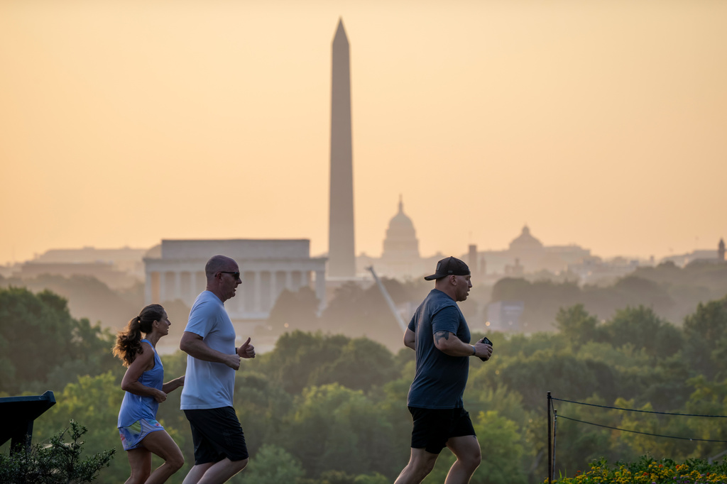 The Lincoln Memorial, Washington Monument, and U.S. Capitol are seen at dawn as joggers run past an overlook in Arlington, Va., Friday, July 3, 2026. (AP Photo/J. Scott Applewhite)