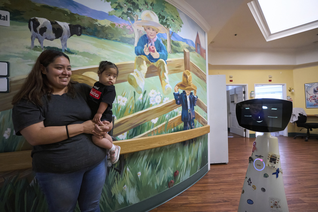 Robin the Robot, developed by Expper Technologies, interacts with Erica Ruiz and her daughter, Valentina, at the HealthBridge Orange Specialty Pediatric Hospital in Orange, Calif., on Friday, Sept. 12, 2025. (AP Photo/Damian Dovarganes)