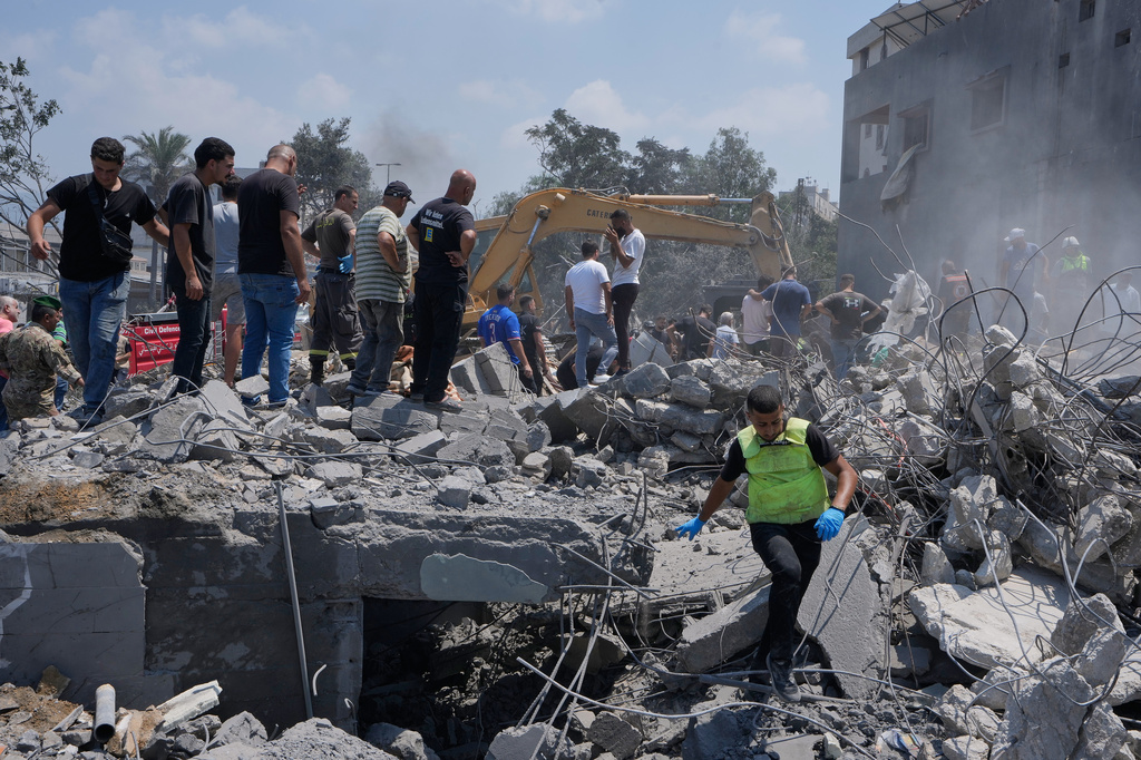 People and rescue workers gather on a destroyed house that was hit by an Israeli airstrike in Deir al-Zahrani village, southern Lebanon, Saturday, Aug. 15, 2026. (AP Photo/Mohammed Zaatari)