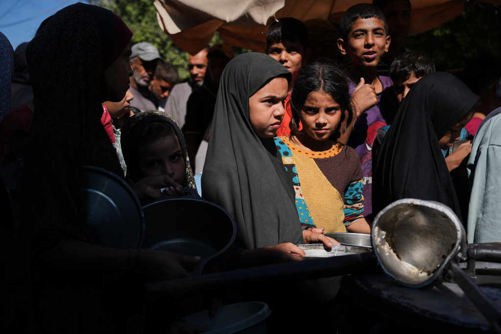 Palestinians receive donated food at a community kitchen in Deir al-Balah, central Gaza Strip, Thursday, Oct. 16, 2025. (AP Photo/Abdel Kareem Hana)