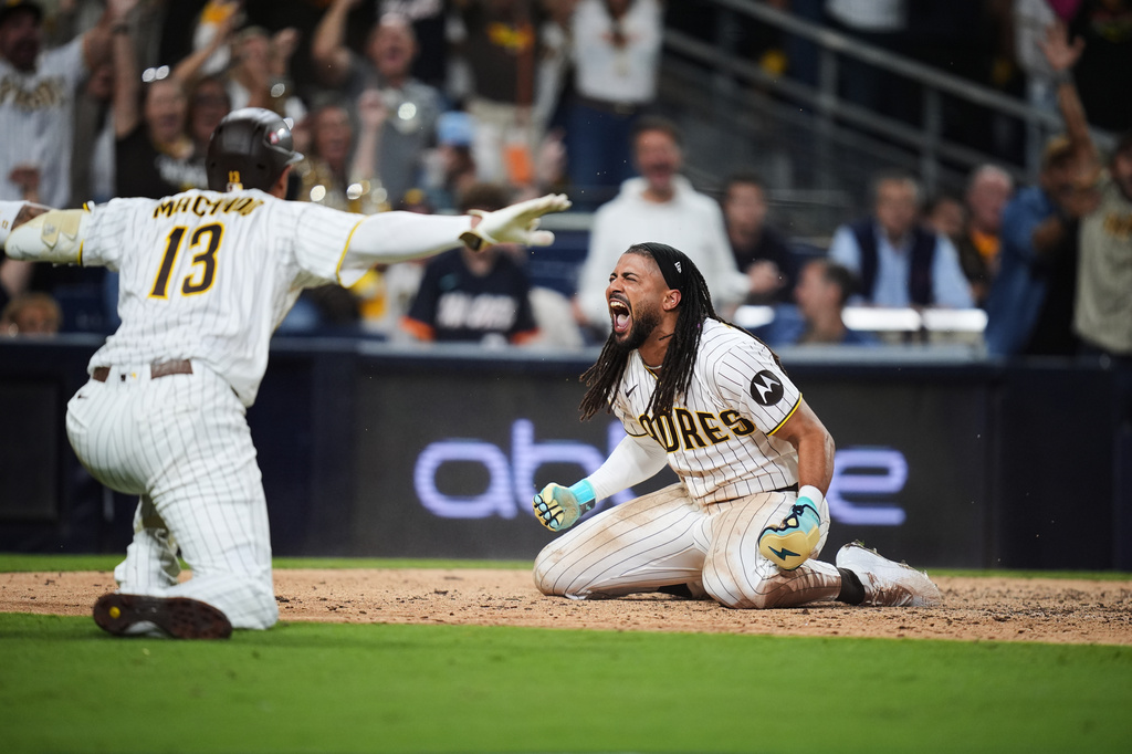San Diego Padres Fernando Tatis Jr. reacts with third baseman Manny Machado (13) after scoring on a steal and an error by Chicago Cubs in the seventh inning of Game 1 of the National League Wild Card baseball playoff series Tuesday, Sept. 29, 2026, in San Diego. (AP Photo/Gregory Bull)