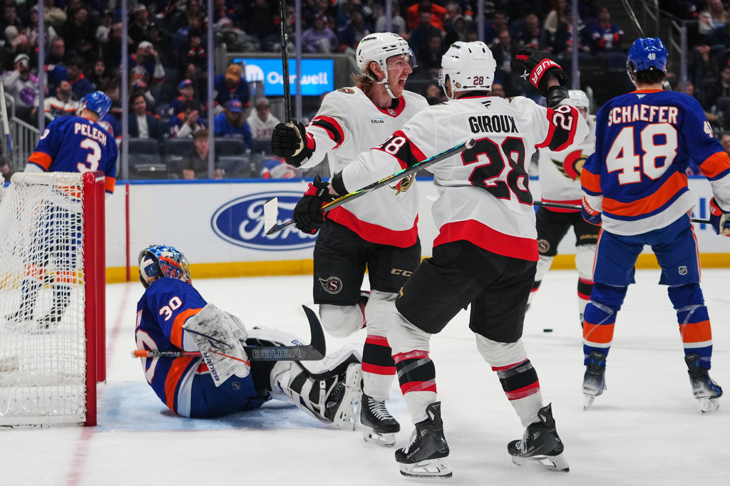 Ottawa Senators' Jake Sanderson (85) celebrates with Claude Giroux (28) after scoring a goal as New York Islanders goaltender Ilya Sorokin (30) watches during the third period of an NHL hockey game Saturday, April 11, 2026, in Elmont, N.Y. (AP Photo/Frank Franklin II)