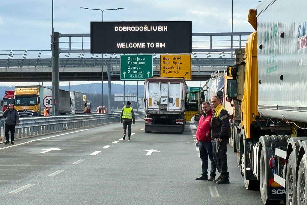 Men stand next to a line of trucks and buses on the Bosnian side of the border with Croatia, in Svilaj, Bosnia, Monday, Jan. 26, 2026, as drivers across the Balkans blocked dozens of border crossings in the region in protest over newly introduced European Union entry regulations.(AP Photo/Eldar Emric)