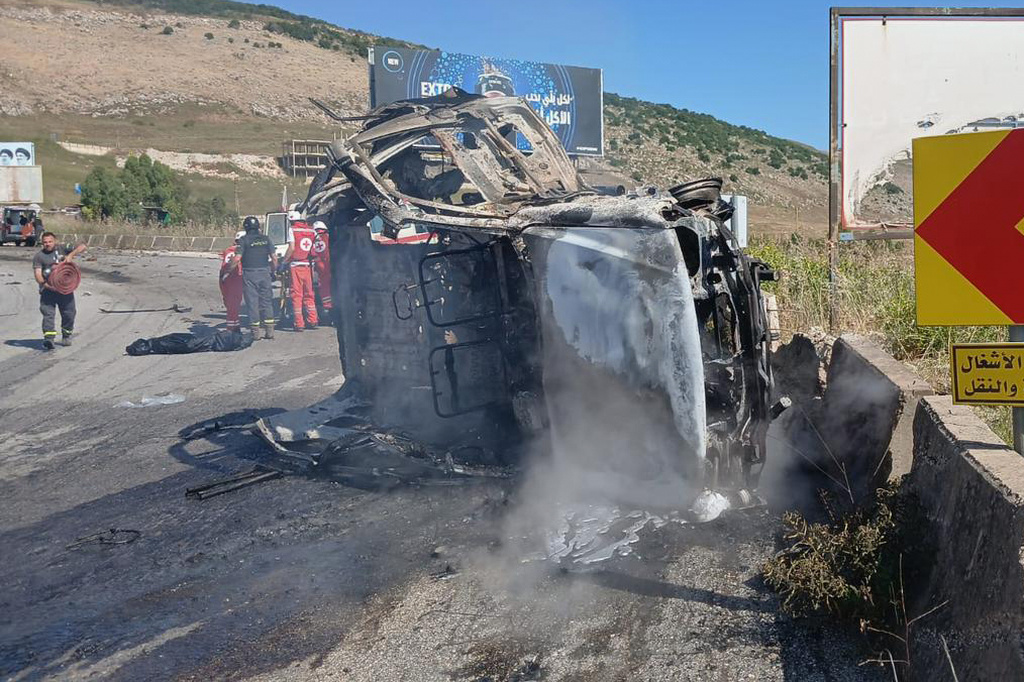 In this image released by the Lebanese Army on its official X account, Lebanese Red Cross personnel and rescue workers stand next to a destroyed vehicle after an Israeli airstrike on the road linking the city of Nabatiyeh and the town of Marjayoun, in Kfar Tebnit, Lebanon, Saturday, June 6, 2026, where, the Lebanese Army said, the vehicle belonged to the army and a brigadier general, a captain and another soldier were killed in the strike. (Lebanese Army via AP)