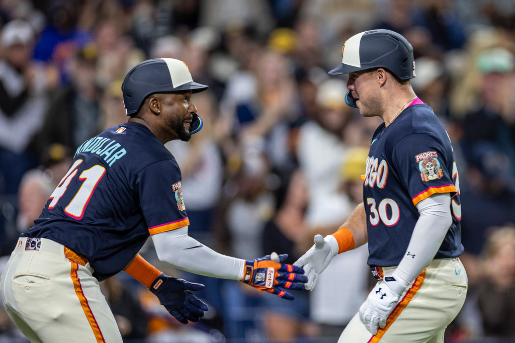 San Diego Padres' Miguel Andujar, left, celebrates a home run by Gavin Sheets (30) in the fifth inning of a baseball game against the Colorado Rockies, Friday, April 10, 2026, in San Diego. (AP Photo/Tony Ding)