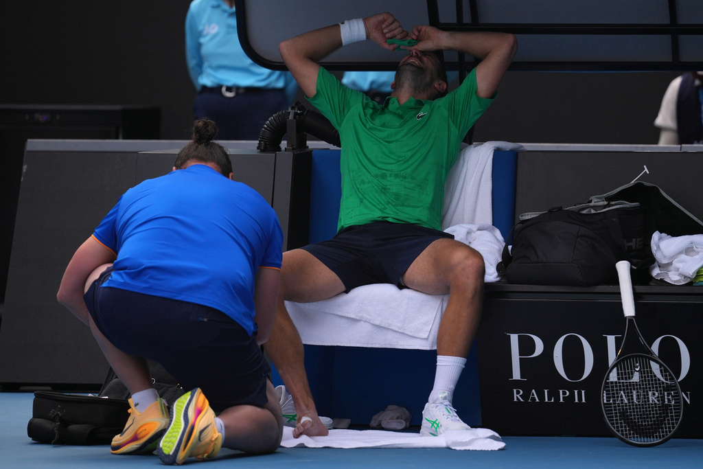 Novak Djokovic of Serbia reacts as he receives treatment to a foot injury during his quarterfinal match against Lorenzo Musetti of Italy at the Australian Open tennis championship in Melbourne, Australia, Wednesday, Jan. 28, 2026. (AP Photo/Dita Alangkara)