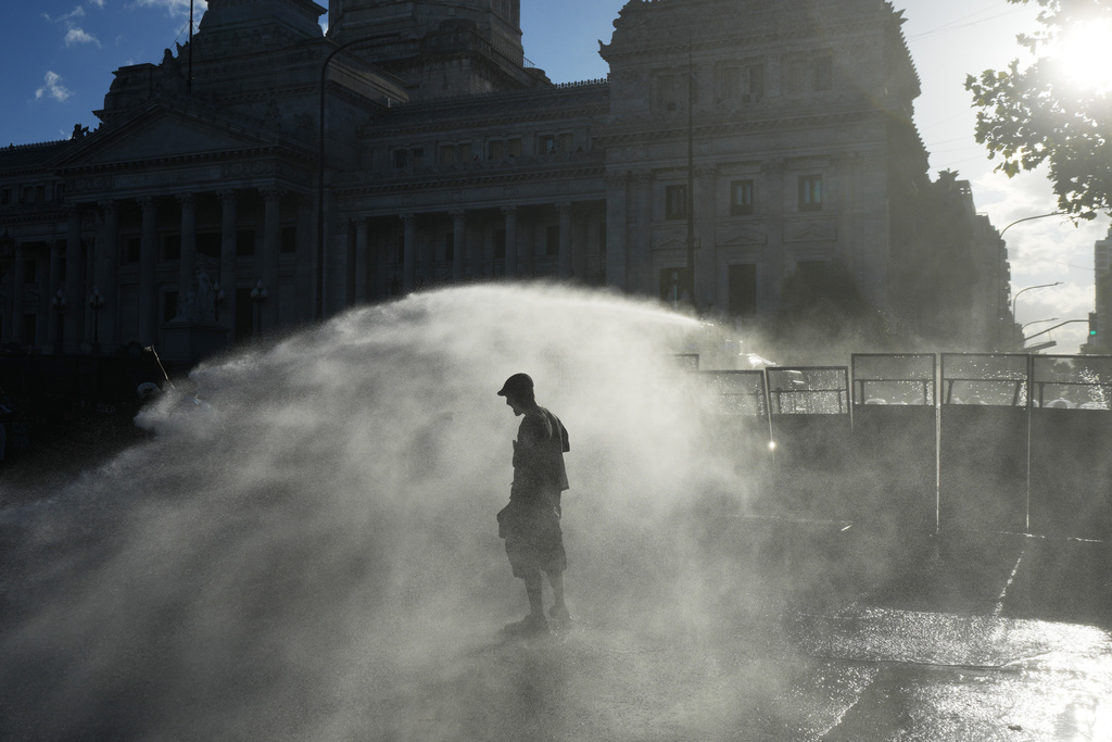 Protesters are sprayed by a police water cannon in front of Congress during a march by trade unions and opposition groups against a labor reform bill proposed by President Javier Milei's government in Buenos Aires, Argentina, Thursday, Feb. 19, 2026. (AP Photo/Rodrigo Abd)