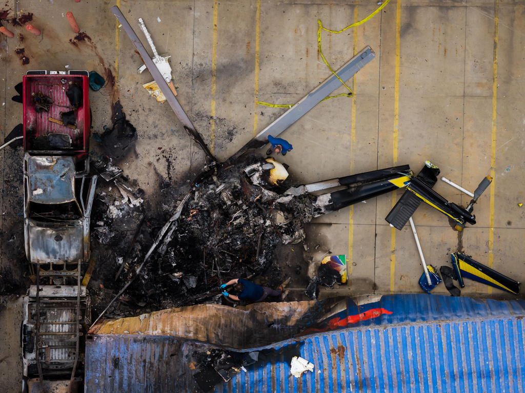 In this aerial view, people investigate the aftermath of a news helicopter crash in Chatsworth, a neighborhood in Los Angeles, on Wednesday, Sept. 16, 2026.(AP Photo/Ethan Swope)