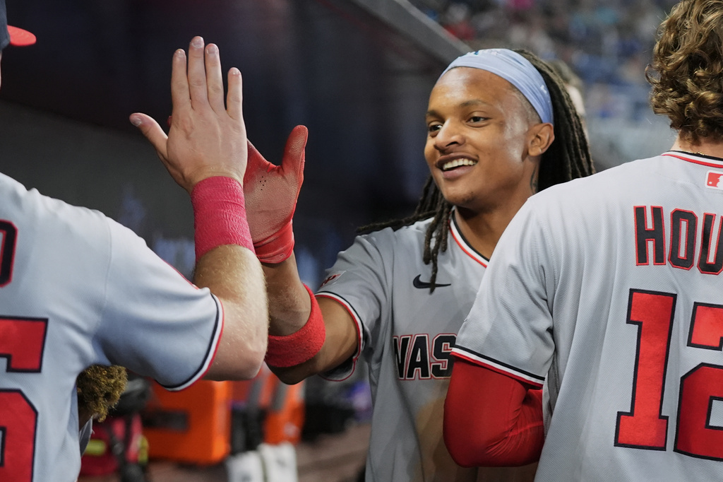 Washington Nationals' CJ Abrams is congratulated in the dugout after scoring on a sacrifice fly hit by Daylen Lile during the third inning of a baseball game against the Miami Marlins, Saturday, May 9, 2026, in Miami. (AP Photo/Lynne Sladky)